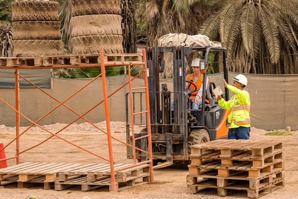 Capacitación grupal en campo con maquinaria pesada